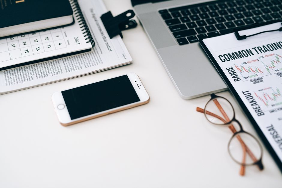A well-organized office desk setup with finance documents, digital devices, and glasses.