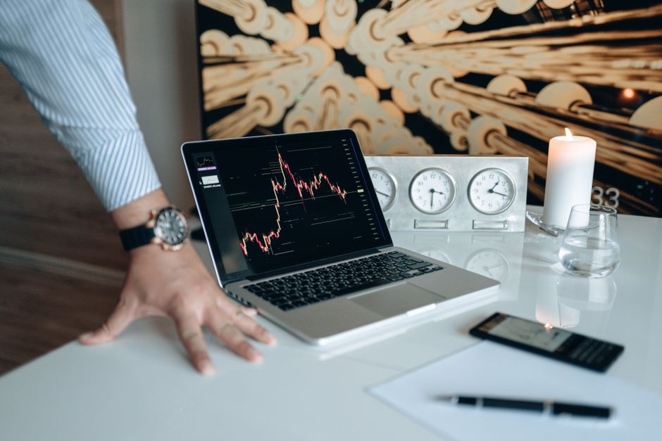 A contemporary desk setting with technology gadgets and a laptop displaying a stock chart.